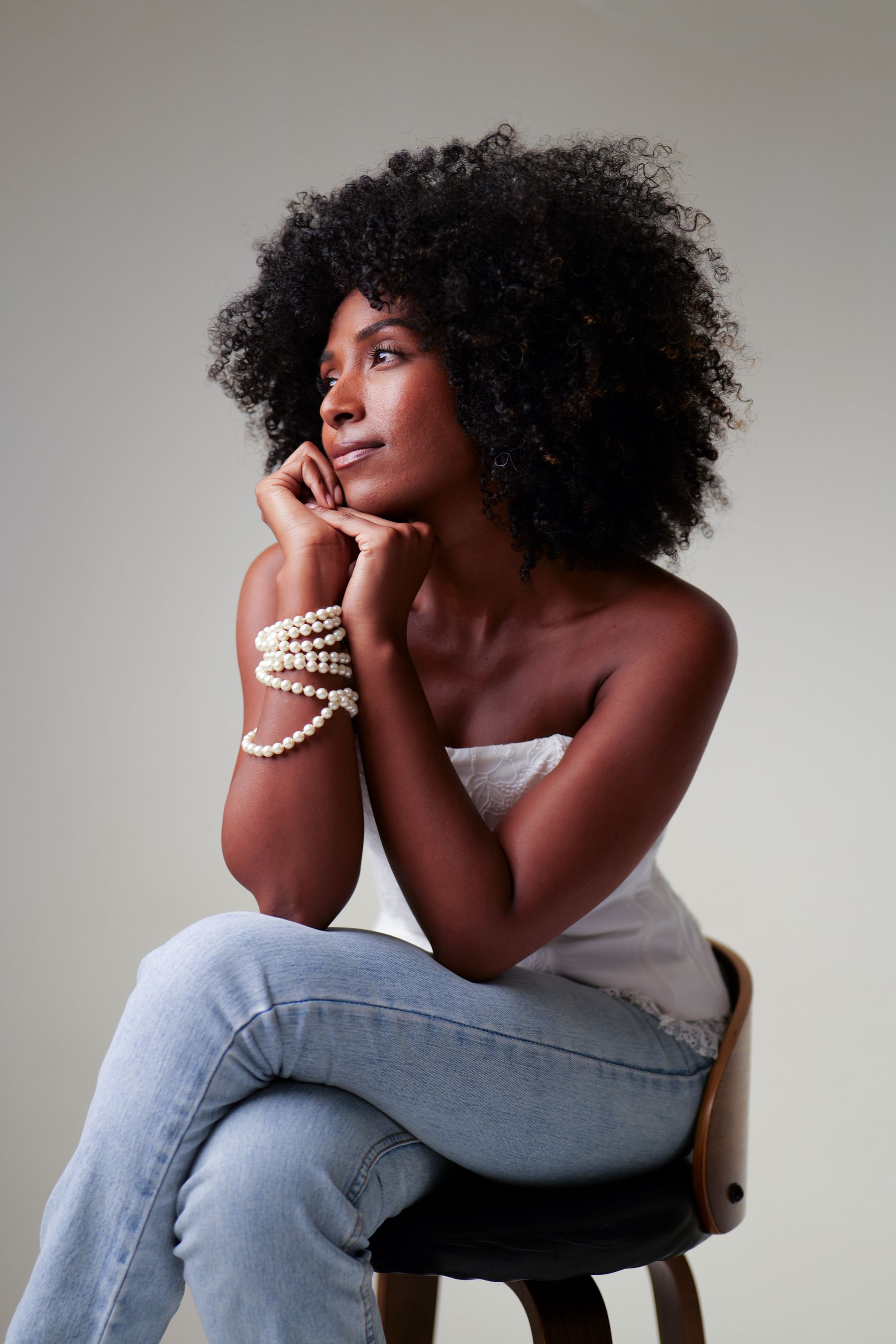 Woman with voluminous natural hair seated on a stool